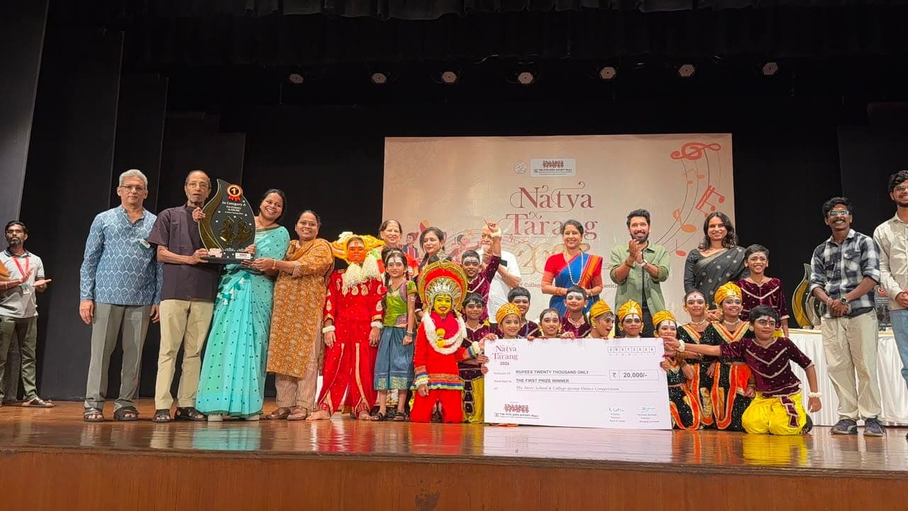 Staff and children in dance costume on stage with a trophy and a giant cheque for twenty thousand rupees, in front of a Natya Tarang 2026 backdrop.