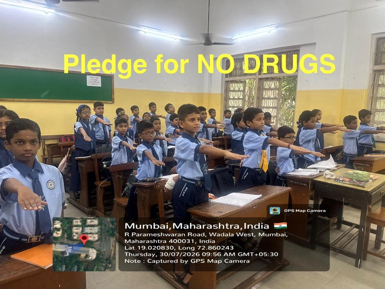 A Secondary class standing at their desks with right arms raised, taking the pledge for a drug-free life.