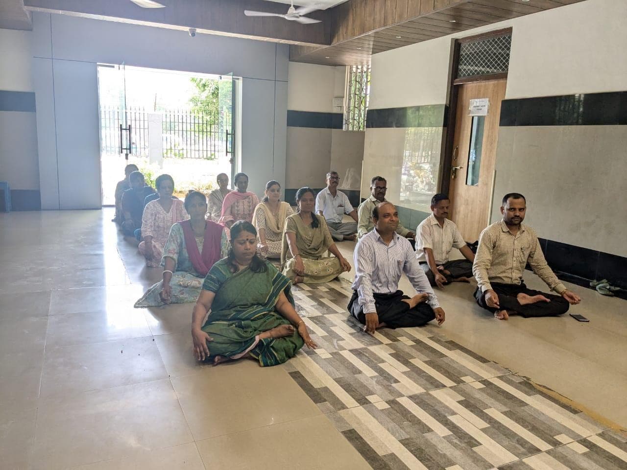 Staff seated cross-legged in the school hall during a guided meditation.