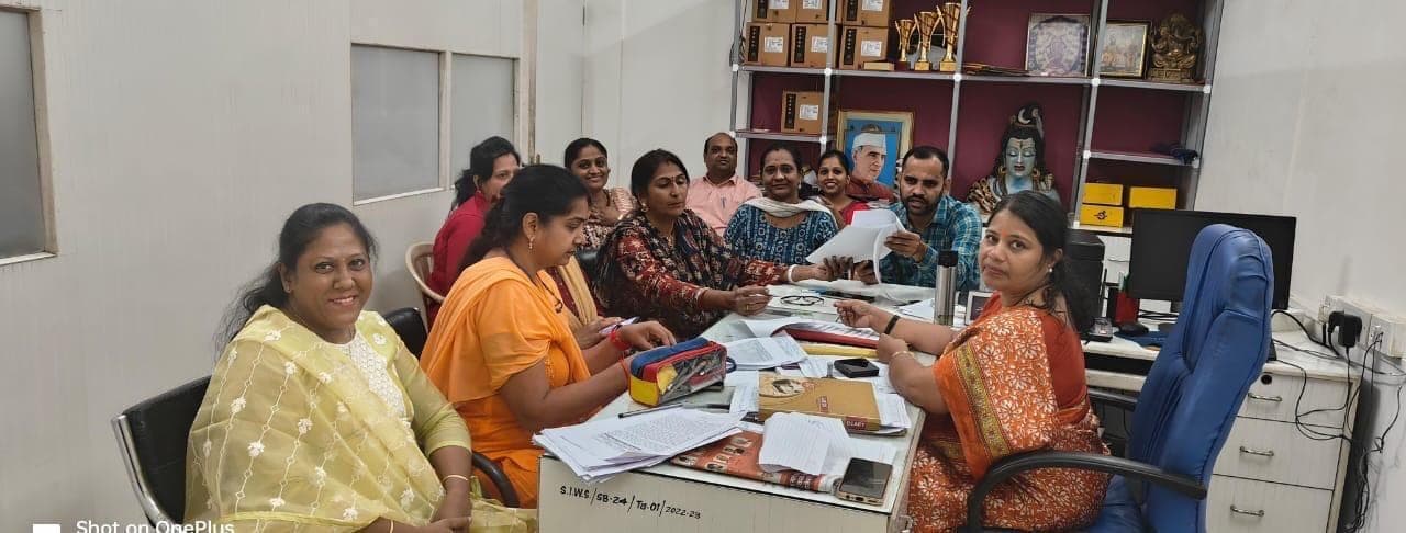 Teachers at work together around a desk in the staff room.