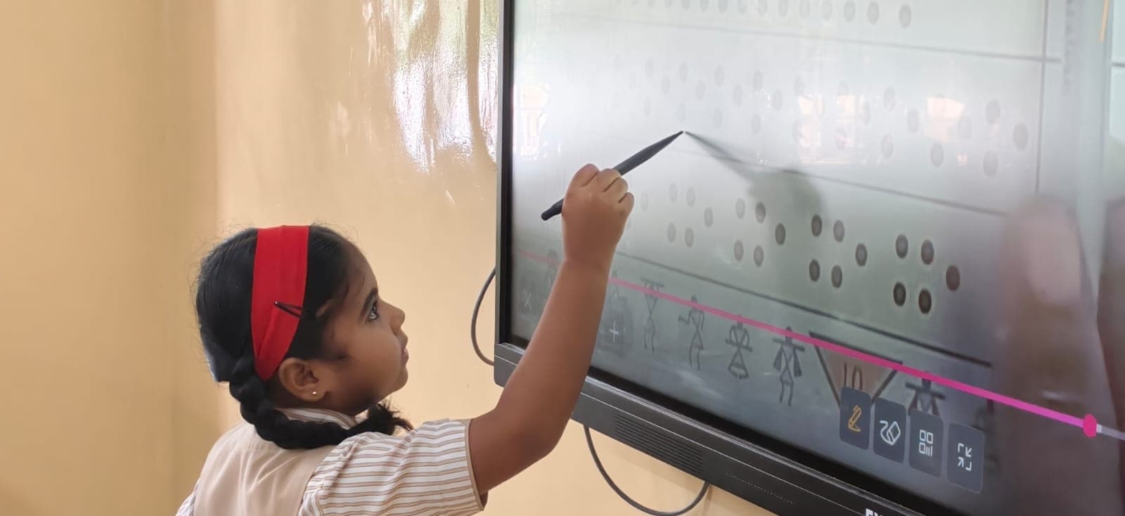 A Primary pupil at the interactive smart board, writing on it with a stylus.